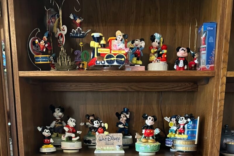 two shelves of Disney toys and memorabilia displayed in cabinet