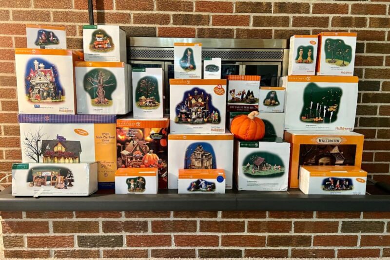 halloween village set in boxes displayed on brick fireplace hearth