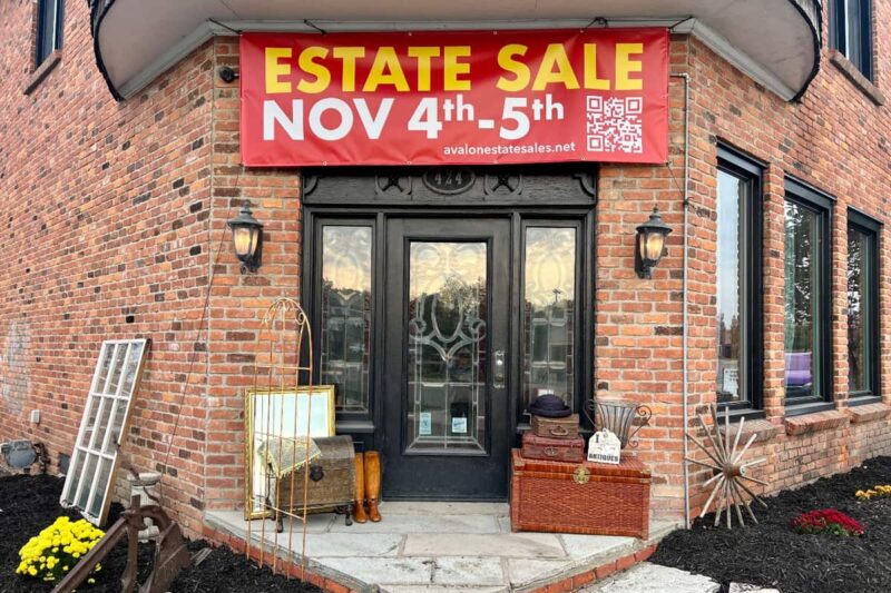 Large banner sign hanging on brick building saying Estate Sale Nov 4th - 5th