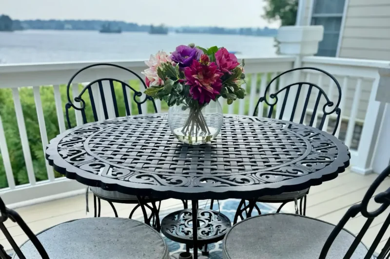 wrought iron patio set with a beautiful bouquet of flowers on a deck overlooking a lake